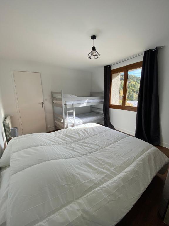 a bedroom with a large white bed and a window at Appartement Le Lauzet in La Roche-de-Rame