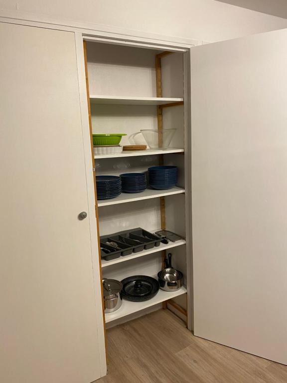 a pantry with white shelves with dishes on them at Appartement Le Lauzet in La Roche-de-Rame