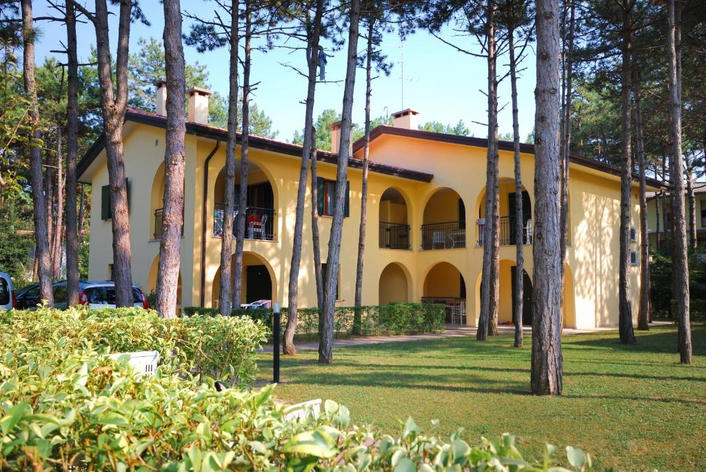 un edificio giallo con alberi di fronte di Villaggio Orchidea a Bibione