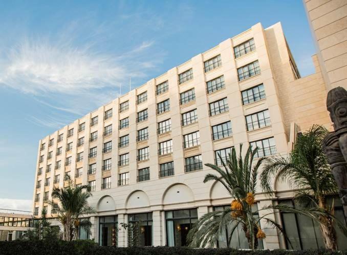 a large building with palm trees in front of it at Grand Palace Hotel in Amman