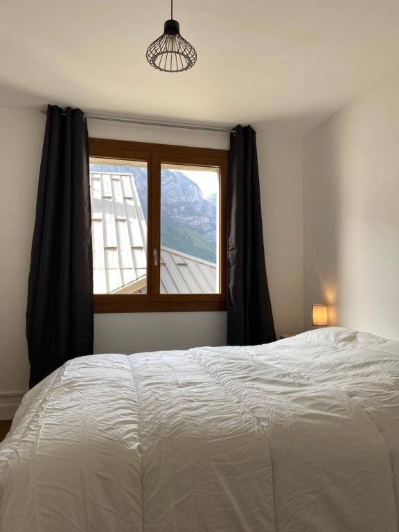 a bedroom with a large bed and a window at Appartement Le Lauzet in La Roche-de-Rame