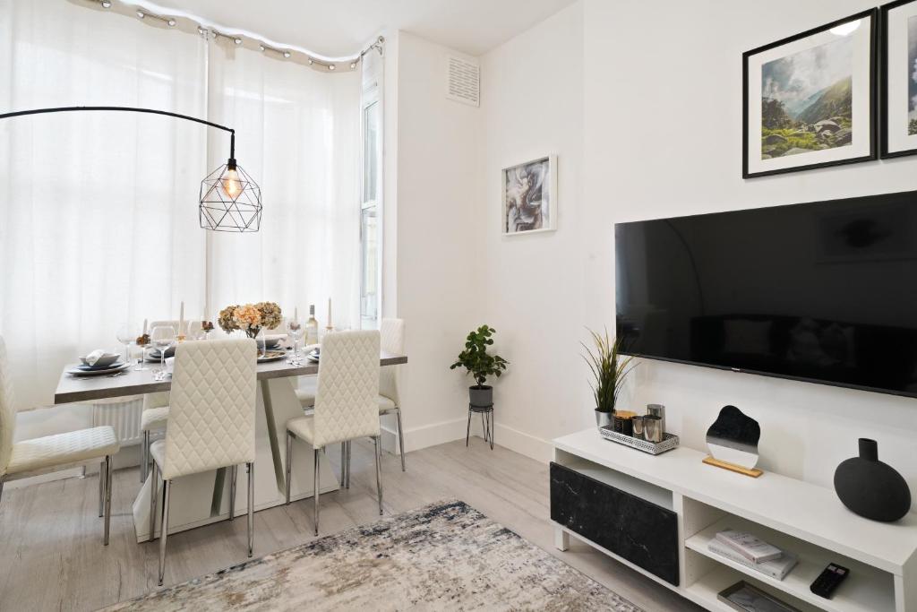 uma sala de estar com uma mesa de jantar e uma televisão em LiveStay-Stylish Two Bed House with Private Garden em Londres