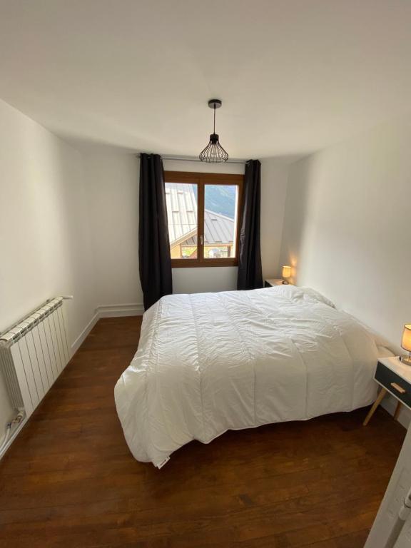 a bedroom with a white bed and a window at Appartement Le Lauzet in La Roche-de-Rame