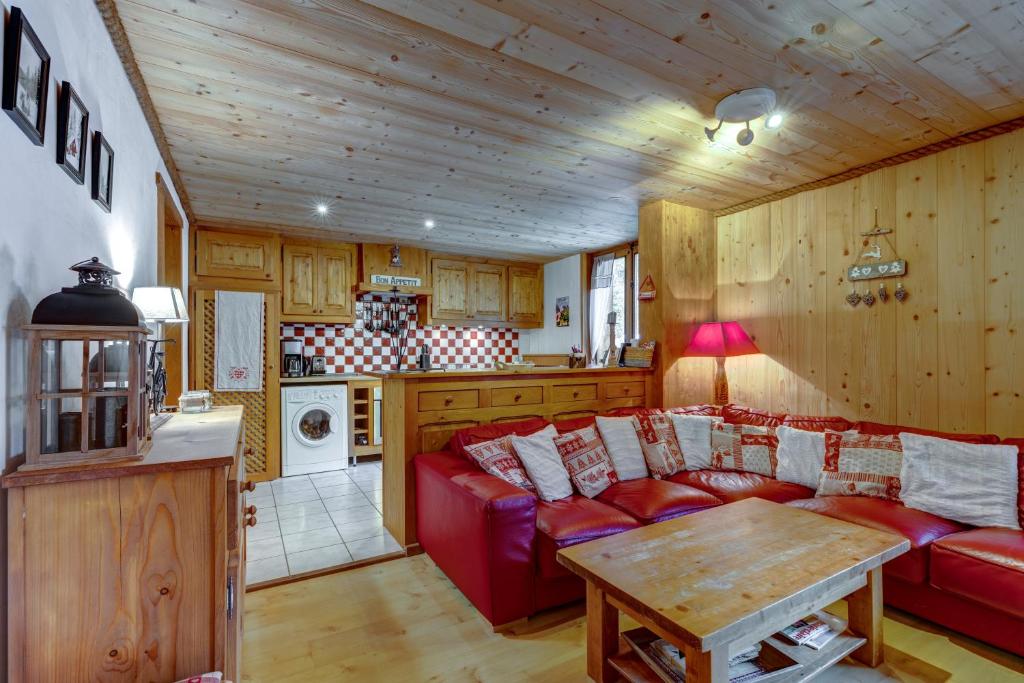 a living room with a red couch and a table at Lou Darbelots in La Giettaz