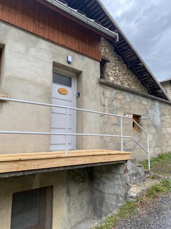 a building with a white door and a wooden porch at Appartement Le Lauzet in La Roche-de-Rame