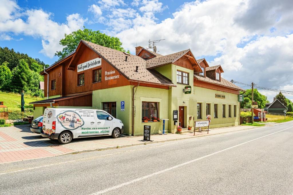 un furgone bianco parcheggiato di fronte a un edificio di Svět pod Ještědem a Hoření Paseky