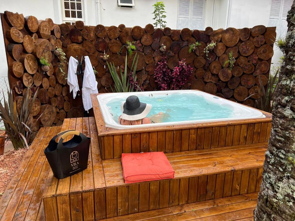 a hot tub with a man in a hat in it at Pousada Vila 505 in Canela