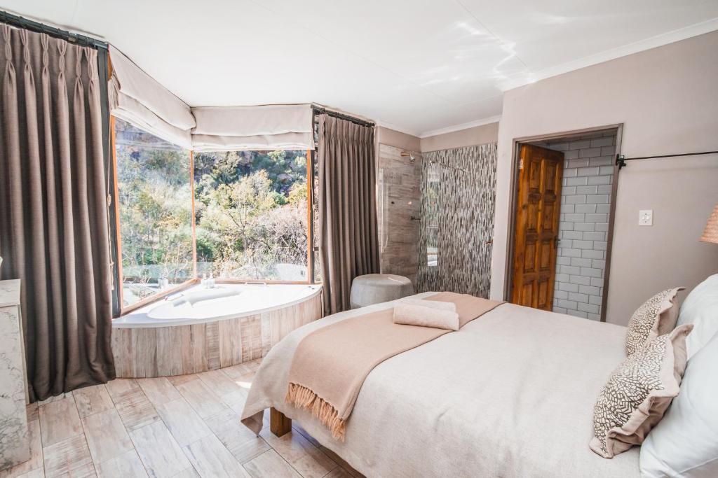 - une chambre avec un lit, une baignoire et une fenêtre dans l'établissement Thabela Thabeng, à Parys