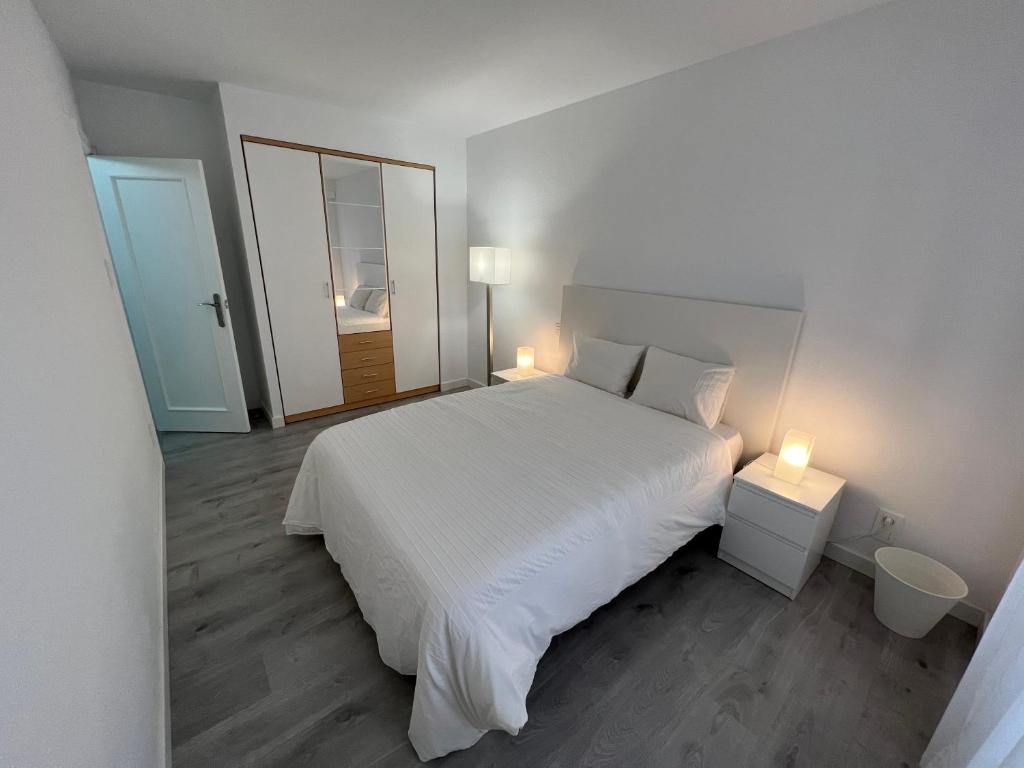 1 dormitorio con 1 cama blanca grande y 2 lámparas en Apartamento 1 dormitorio cerca hospitales, en Zaragoza