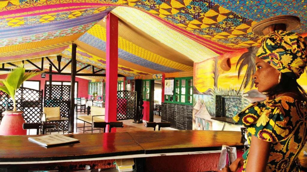 a woman standing in front of a table in a restaurant at Eco-Lodge Hotel Oasis Fishing in Saint-Louis