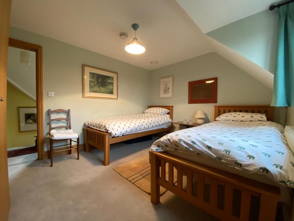 a bedroom with two beds and a chair at Jasmine Cottage in Frome