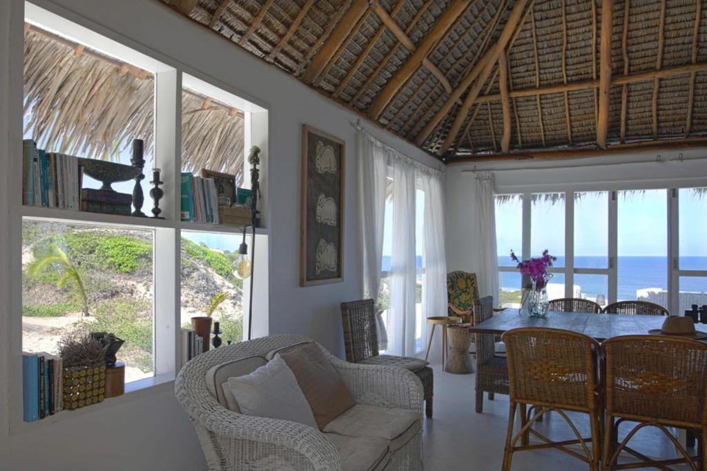 un soggiorno con tavolo, sedie e finestre di Mar-Me-Quer, Eco Beach Retreat a Inhambane