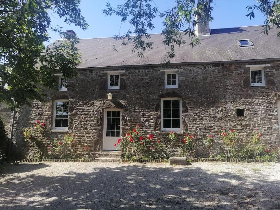 una casa de piedra con flores rojas delante de ella en Gîte Les Aubins - Bord de Mer - Cotentin, en Bretteville-sur-Ay