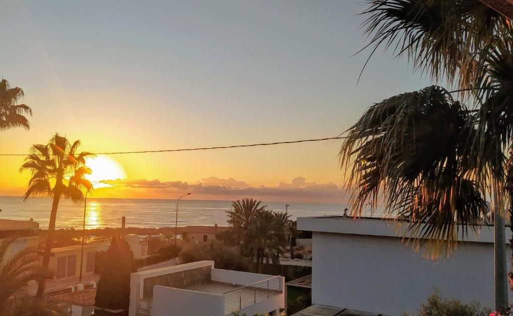un tramonto sull'oceano con palme e un edificio di Nuza, Villa con Piscina y Barbacoa a El Campello