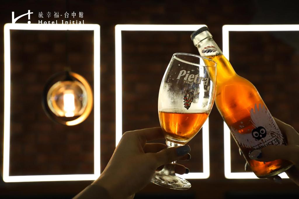 a person holding a glass with a bottle of beer at Hotel Initial-Taichung in Taichung