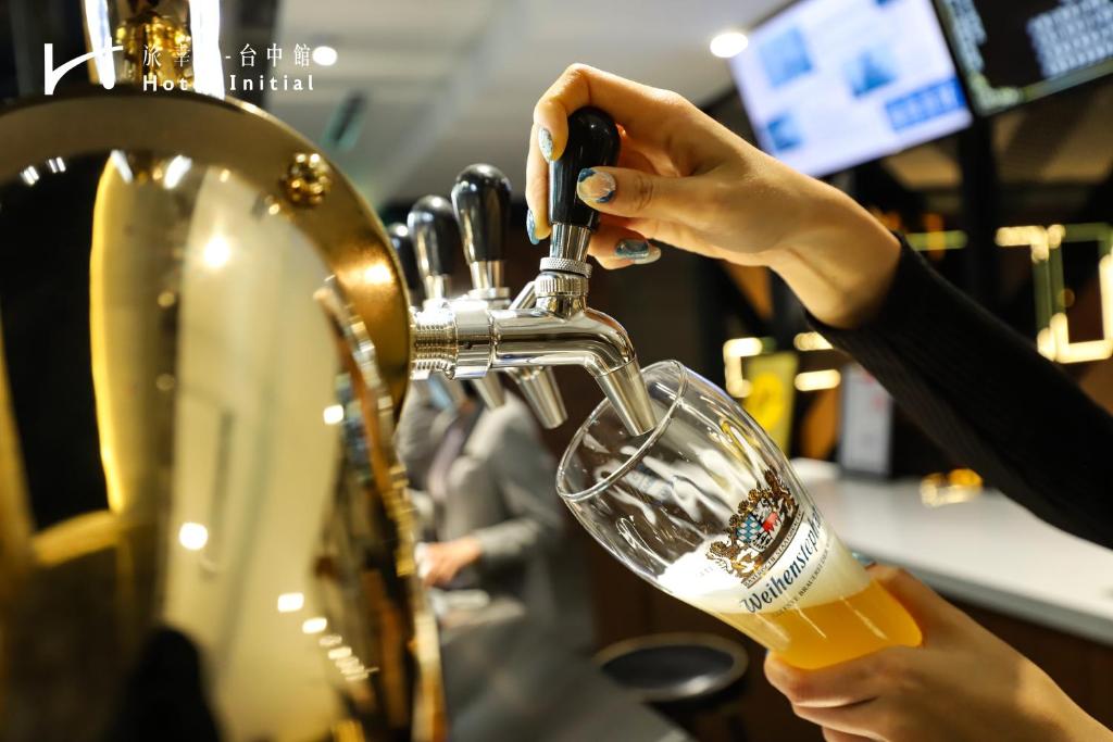 a woman pouring a beer into a glass at Hotel Initial-Taichung in Taichung