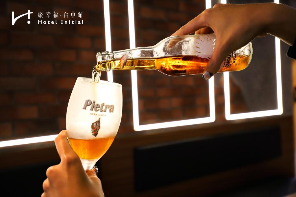 a person pouring a beer into a glass at Hotel Initial-Taichung in Taichung
