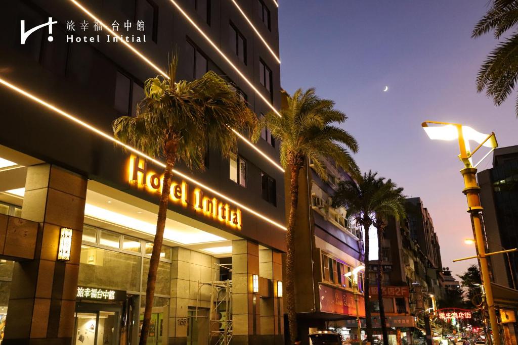 a building with palm trees in front of it at Hotel Initial-Taichung in Taichung