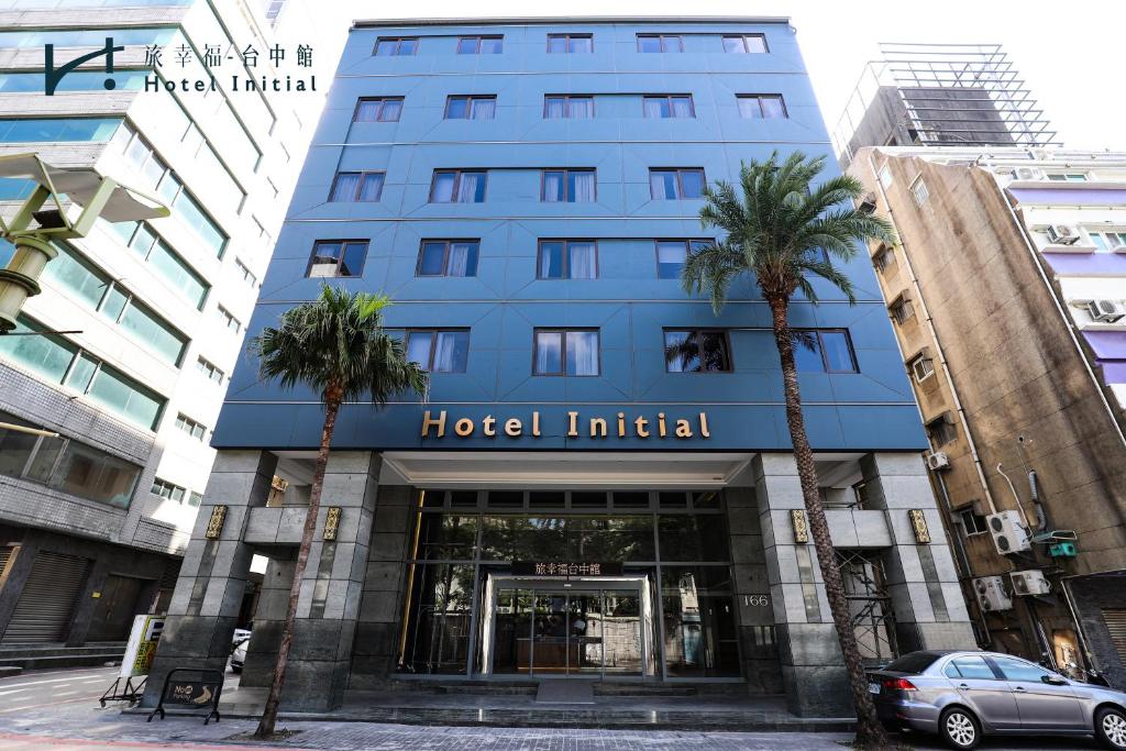 a blue hotel with palm trees in front of it at Hotel Initial-Taichung in Taichung