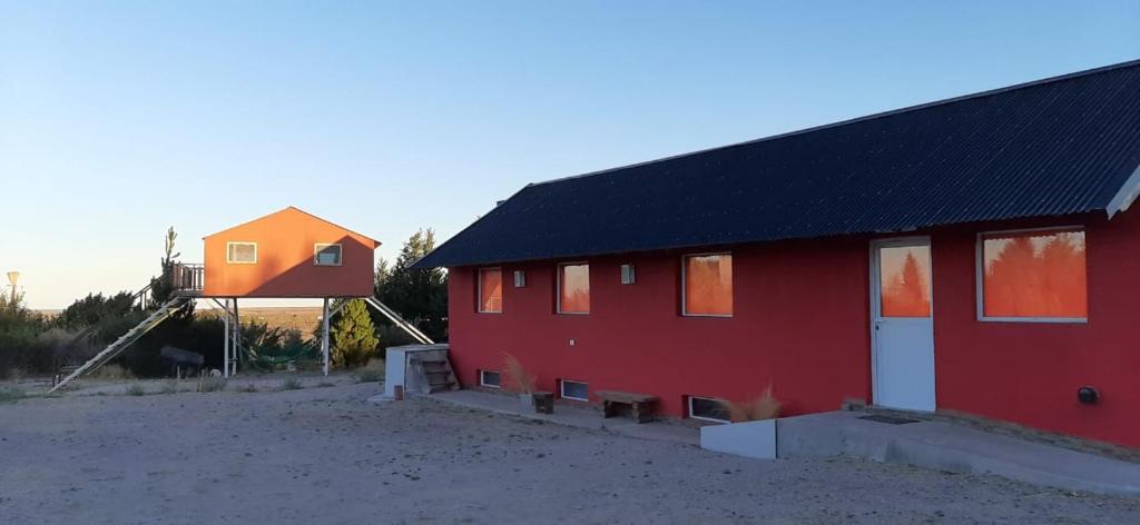 un granero rojo con una casa naranja al lado en Tres Piquillines en 