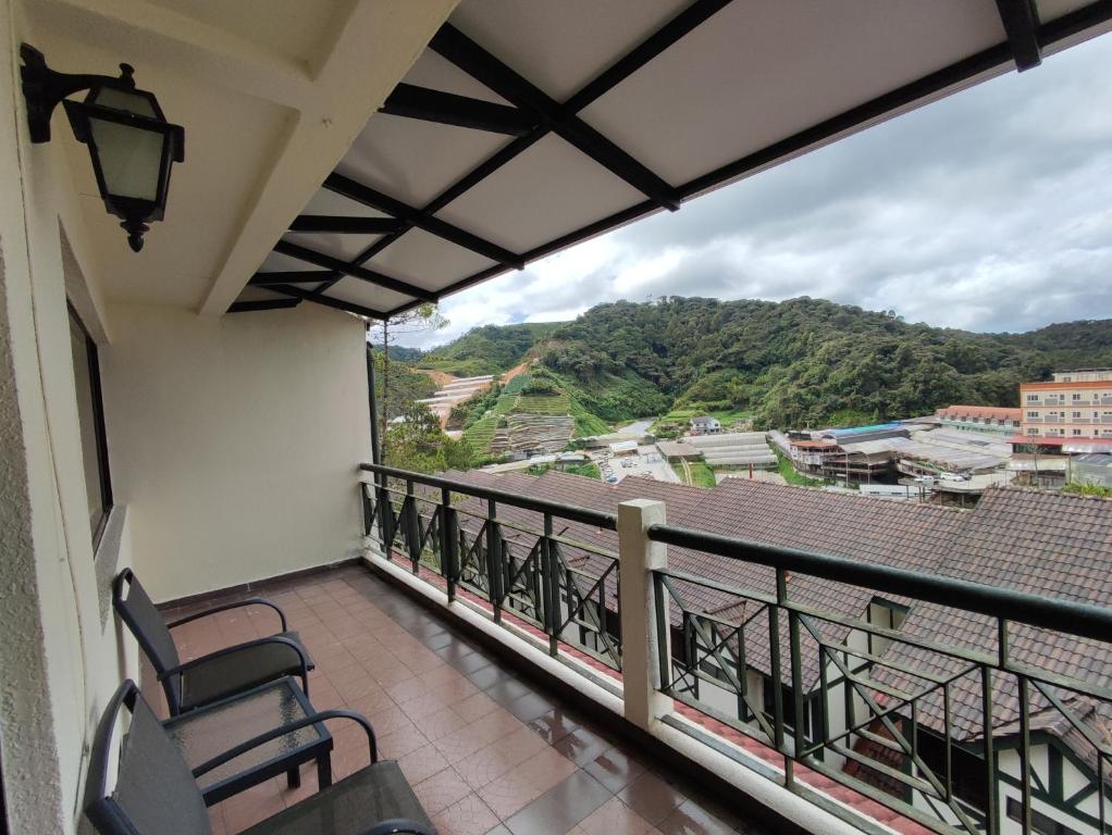 un balcon avec des chaises et une vue sur une ville dans l'établissement Awesome Homestay Apartment @ Equatorial Hill Resort, à Brinchang