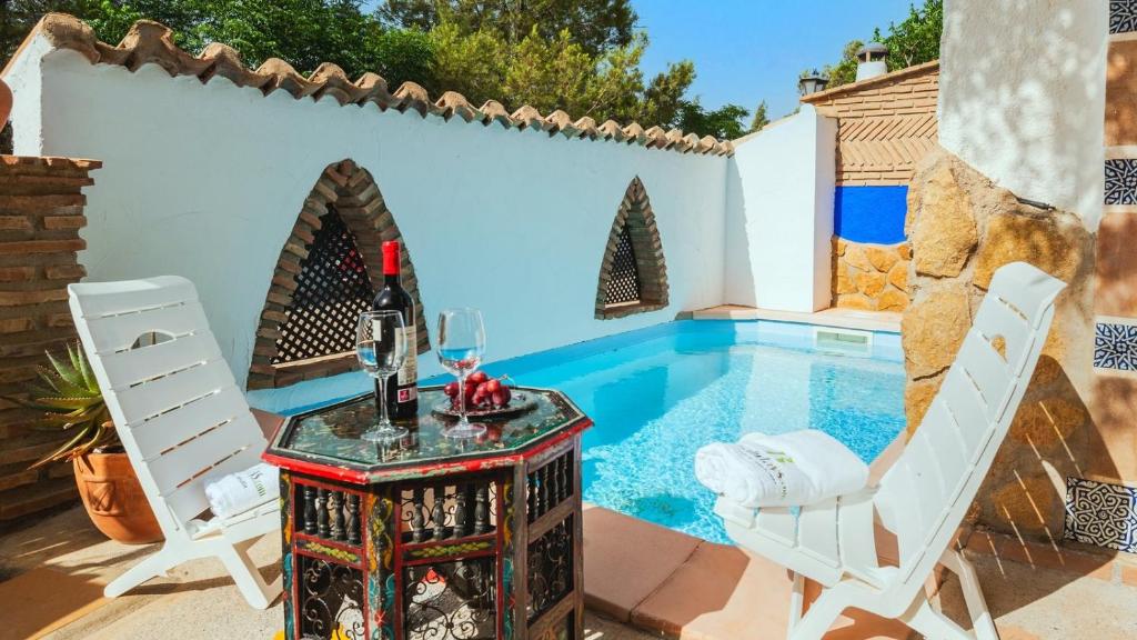 eine Terrasse mit einem Pool und einem Tisch mit Weingläsern in der Unterkunft Cueva del Tito Hinojares by Ruralidays in Hinojares