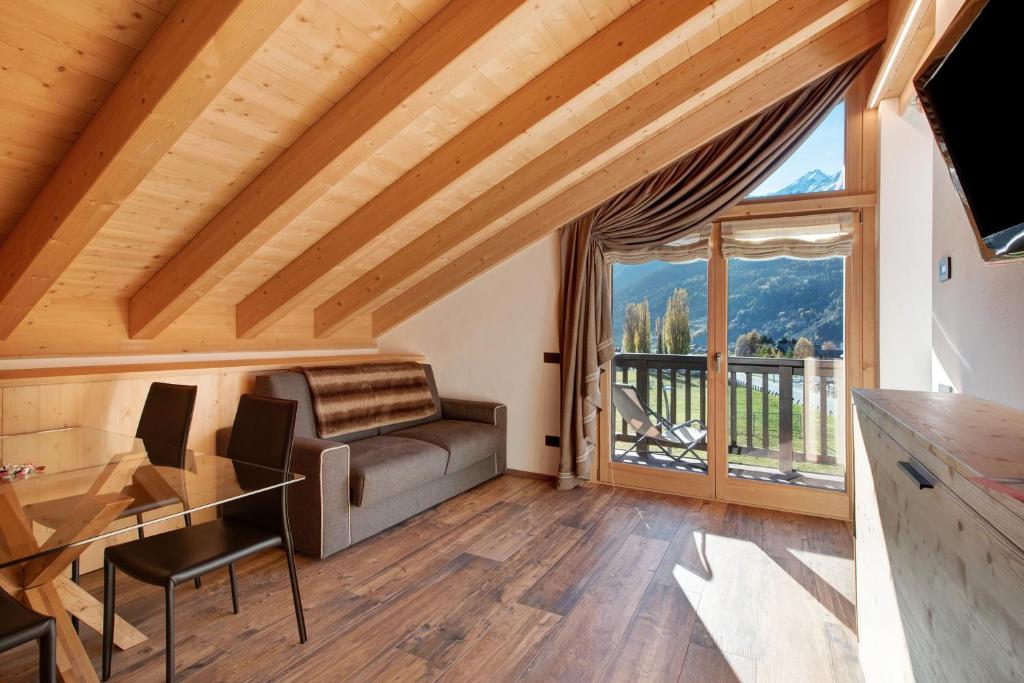 een woonkamer met een bank en een groot raam bij Olympic Chalet 13 in Bormio