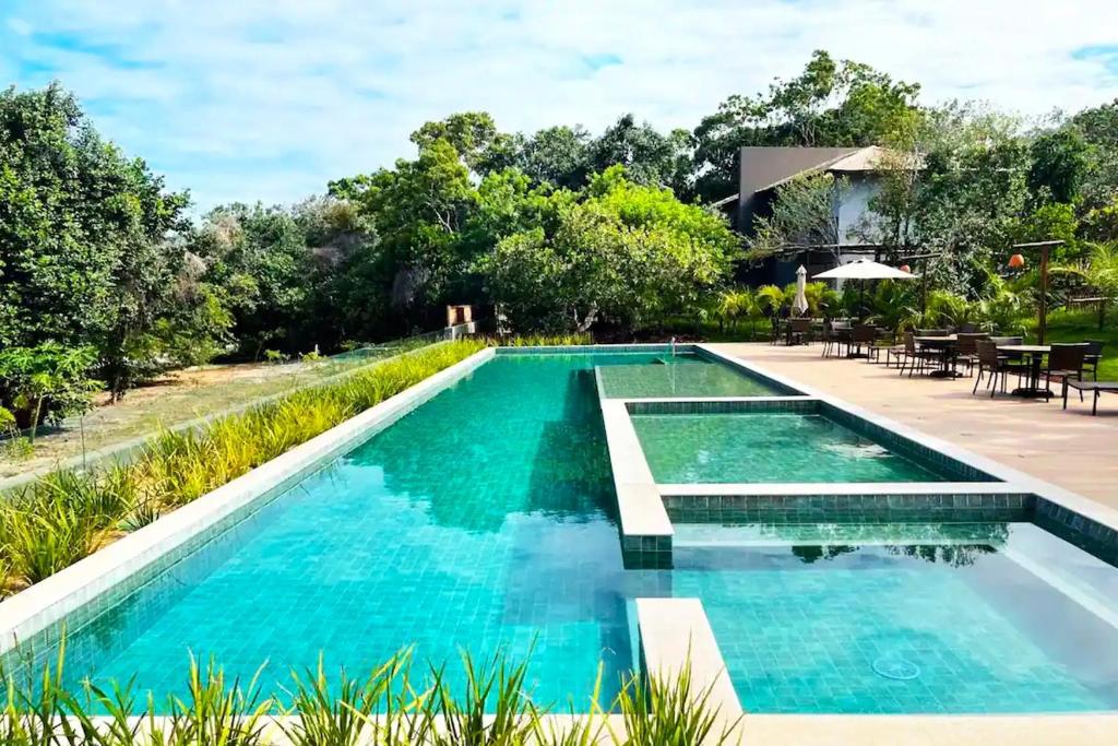 Casa Praia do Forte Bahia Jardim Piscina Churrasco في برايا دو فورتي: مسبح بمياه زرقاء واشجار