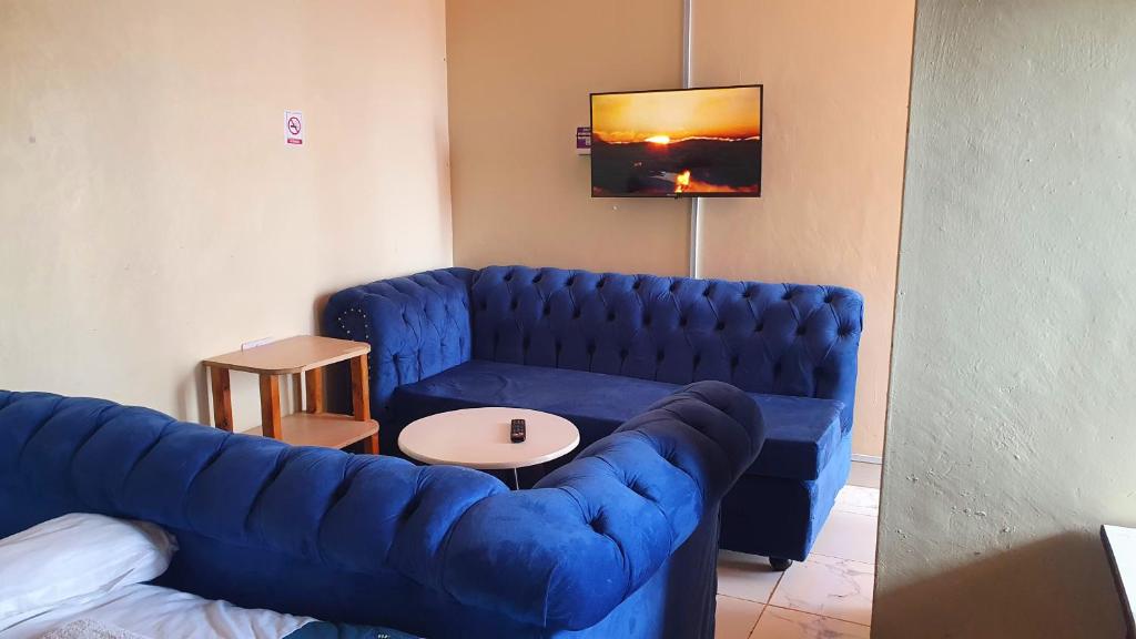 uma sala de estar com um sofá azul e uma mesa em Lola's Nest along the Highway - Free Parking, Wifi, Netflix & Rooftop views em Kikuyu