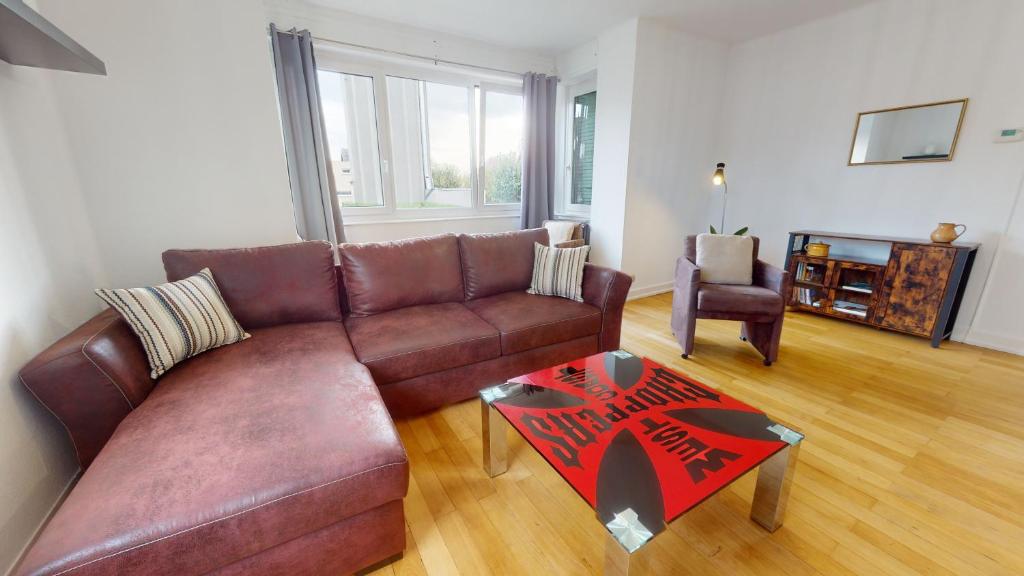 - un salon avec un canapé en cuir brun et une table dans l'établissement Appartement Le Passage - Ostheim, à Ostheim
