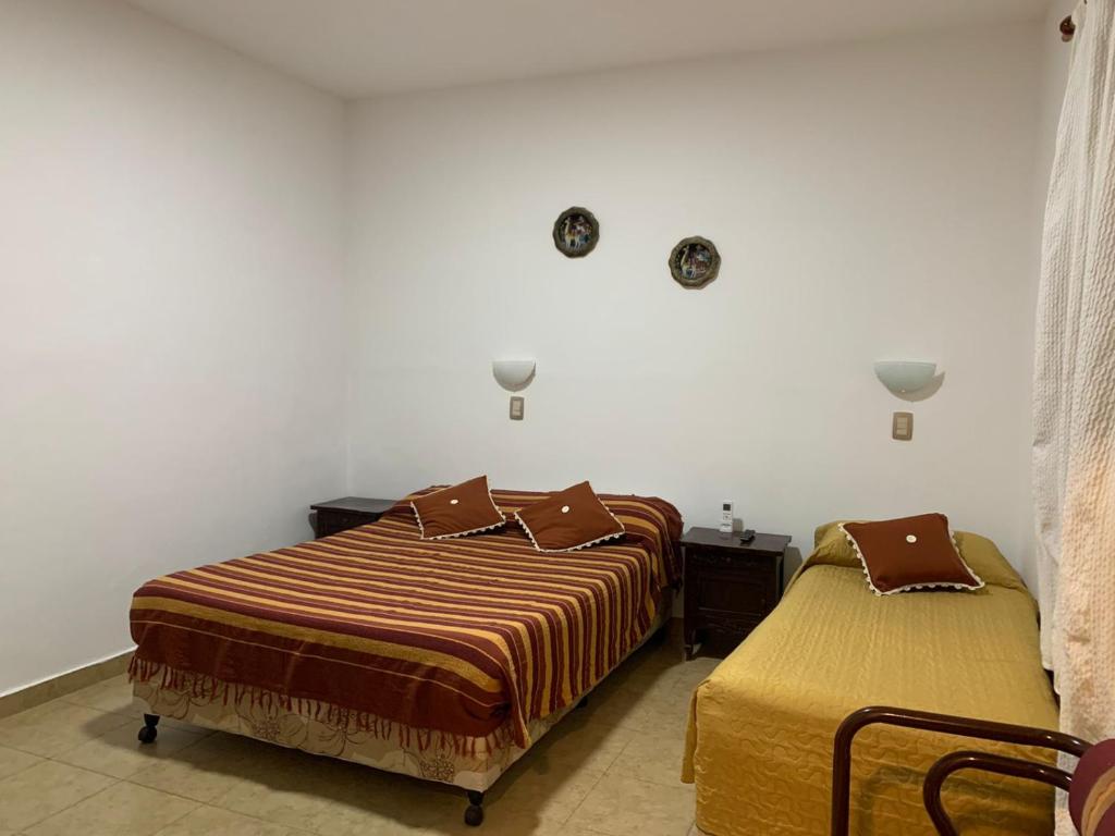 two beds in a hotel room withskirts at Hotel Residencial España in Salta