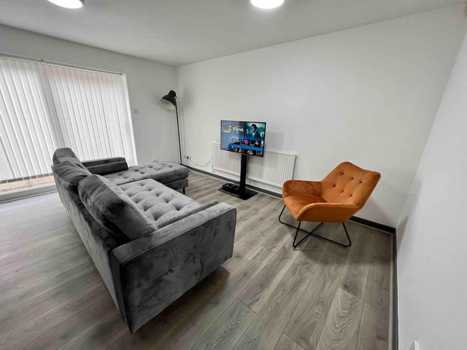 ein Wohnzimmer mit einem Sofa und einem Stuhl in der Unterkunft 3 bedroom house with parking in Manchester
