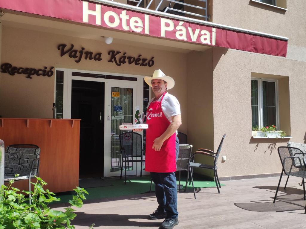 ハイドゥソボスローにあるHotel Pávaiのホテルの前に立つ帽子の男