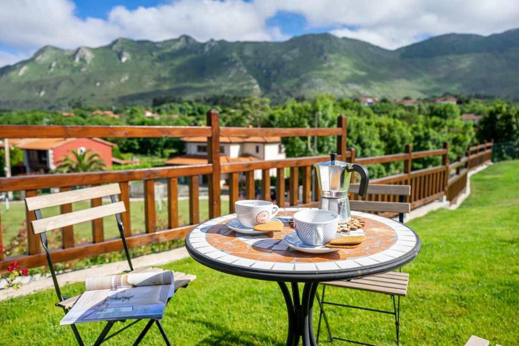 einen Tisch mit Tassen und einen Krug auf einem Balkon mit Bergen in der Unterkunft Precioso apartamento cerca de playas y Picos de Europa Apto Reno Rexidora in Cuerres