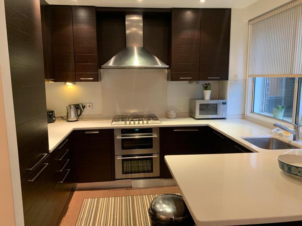 a kitchen with brown cabinets and a stove top oven at Lovely 3 bedroom apartment in London