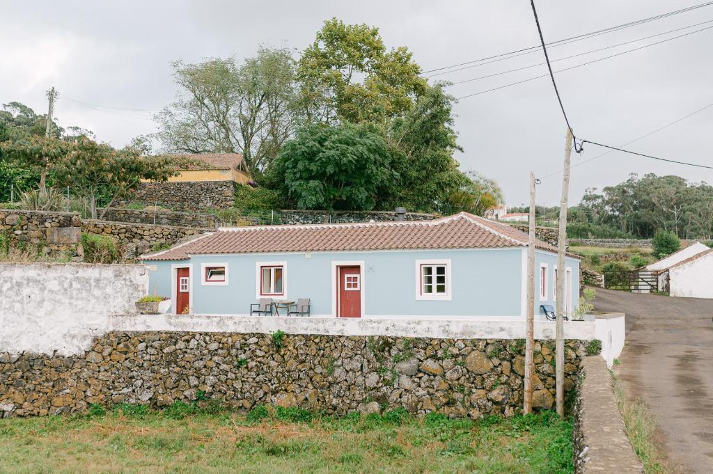 une maison blanche derrière un mur en pierre dans l'établissement Casa Ver o Mar, à São Mateus