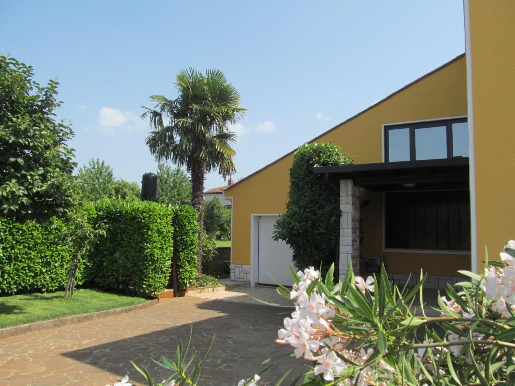 a house with a palm tree and a garage at Apartments ZVEZDICA*** with garden in Zambratija