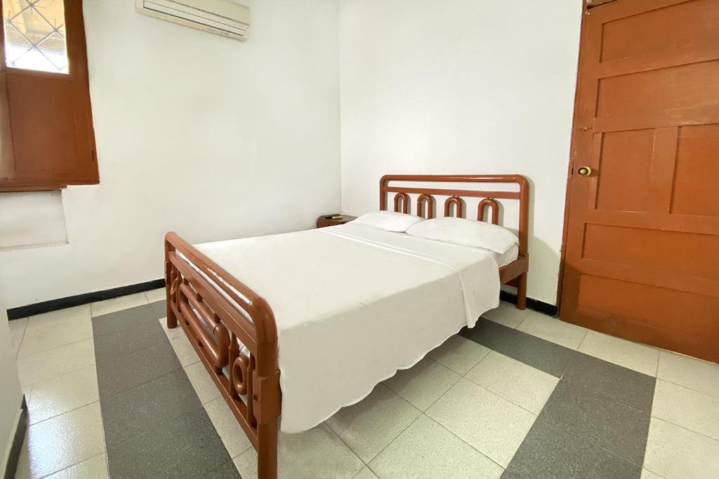 sypialnia z drewnianym łóżkiem z białą pościelą w obiekcie Hotel Ayenda Republicano Colonial No 2 w mieście Santa Marta