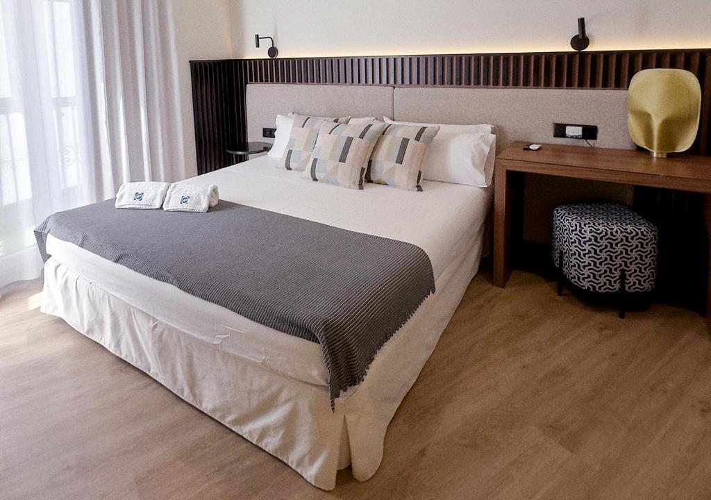 a bedroom with a large bed and a desk at ISA Sevilla Suites in Seville
