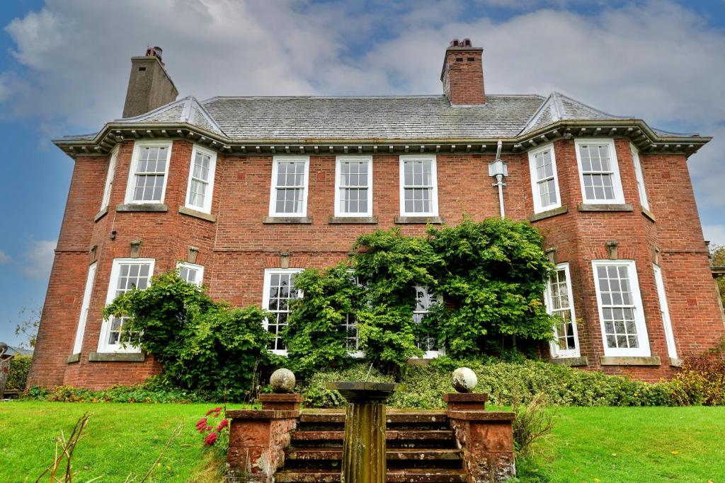 a large red brick house with white windows at Finest Retreats - Edwardian Country House - 9 Bed, Sleeping up to 21 in Longtown