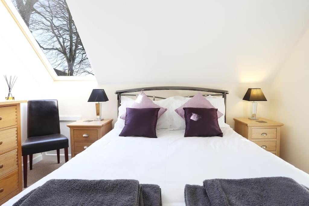 a bedroom with a large white bed with purple pillows at THE DEN, a Secluded Annex, Hot-tub, Heating & Breakfast in Long Bredy