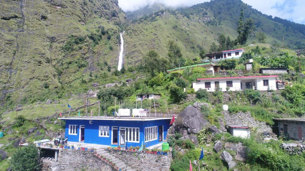 una casa blu sul fianco di una montagna di Green Mountain Homestay - Birthi Falls near Munsyari a Munsyari