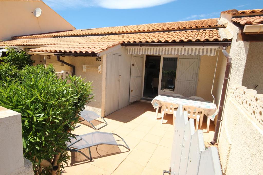 une terrasse avec une table et des chaises dans une maison dans l'établissement Belle villa 5 couchages terrasse Sud parking dans résidence sécurisée piscine commune 400m de la mer LRJP102, à Portiragnes