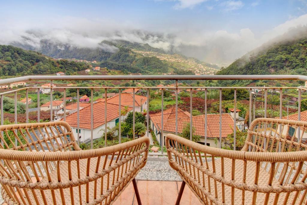 a balcony with chairs looking out at the mountains at Vinháticos House in São Vicente