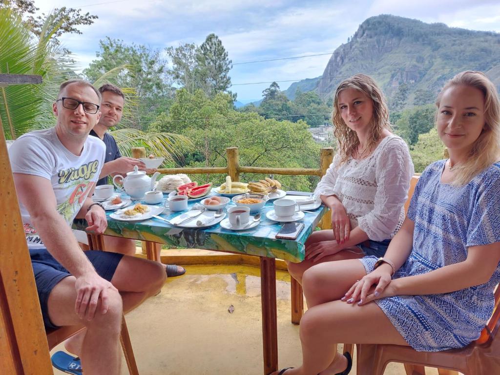 un grupo de personas sentadas alrededor de una mesa con comida en Eden View Ella - Tour options in the area, en Ella