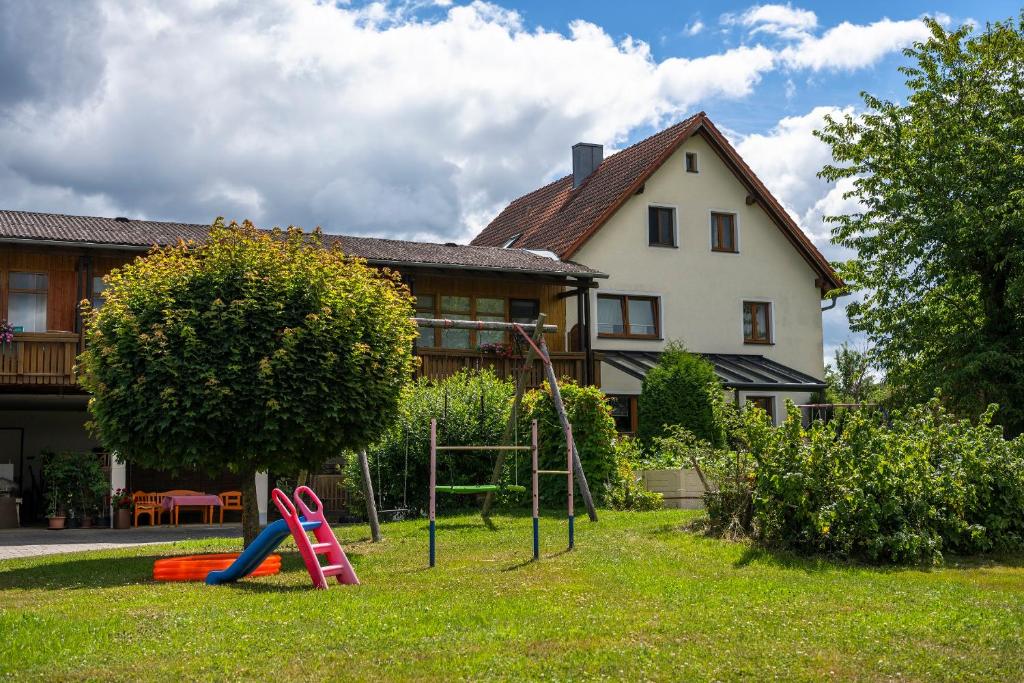 a yard with a playground in front of a house at Ferienwohnung Haus Inge in Moosbach
