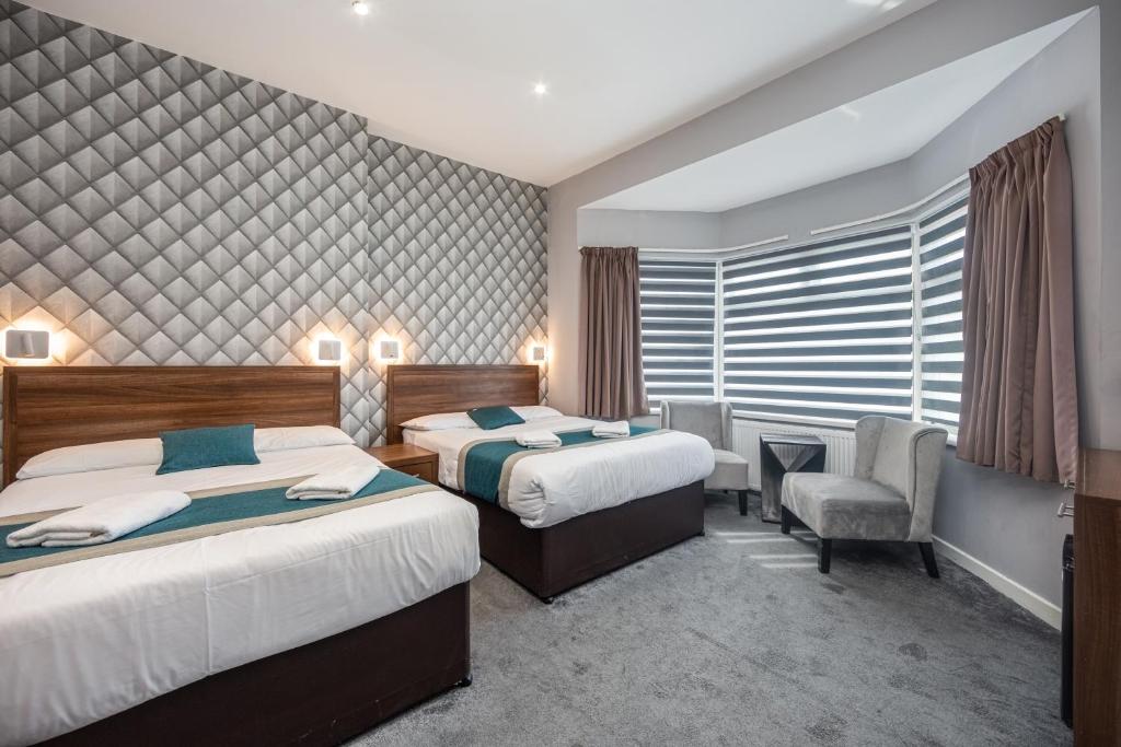 una habitación de hotel con 2 camas y una silla en King Solomon Hotel- Golders Green en Londres