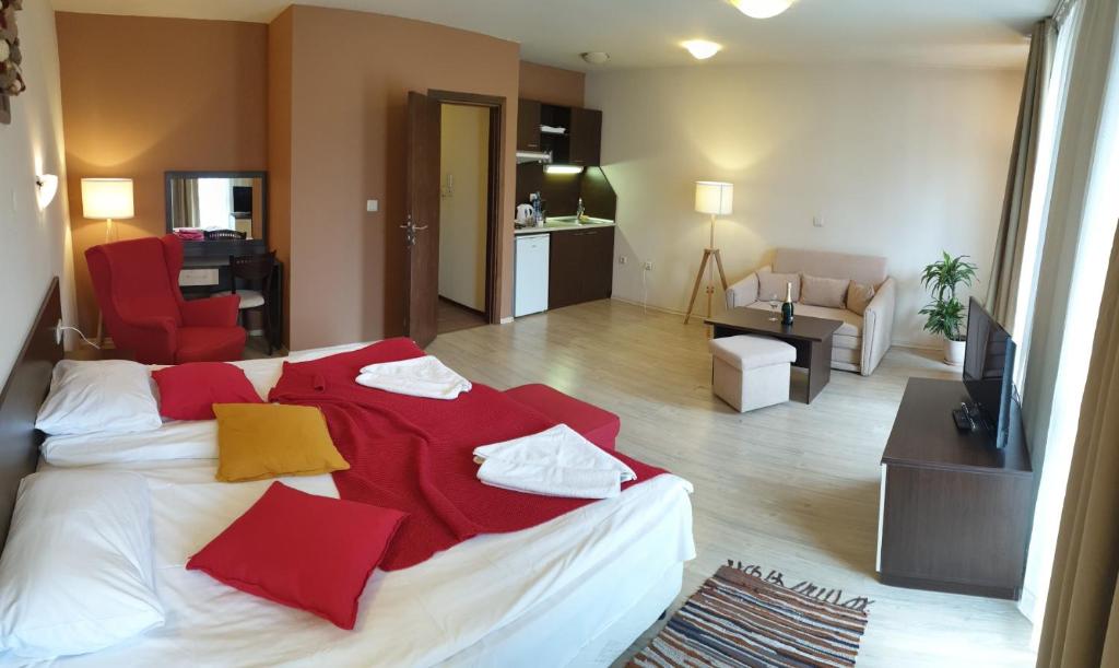 1 dormitorio con 1 cama grande con almohadas rojas y amarillas en Banderitsa Apartments with kitchen & BBQ, en Bansko