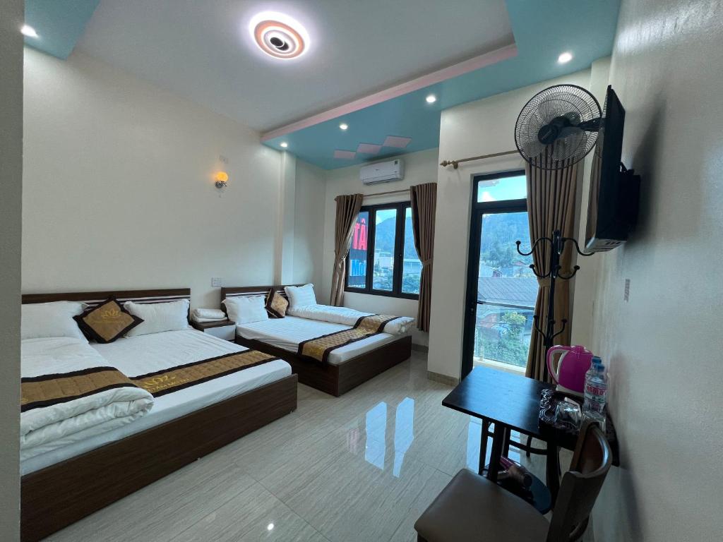 a bedroom with two beds and a couch and a table at Thái Tâm MOTEL in Dồng Văn