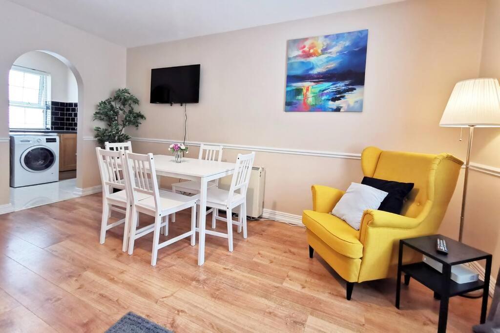 a living room with a dining room table and a yellow chair at Spacious 2bed apartment city centre in Dublin